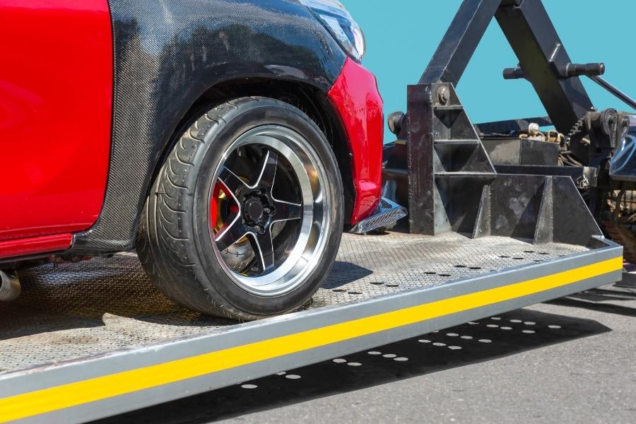 sport red vehicle close up on top of towing truck gonzalez tx